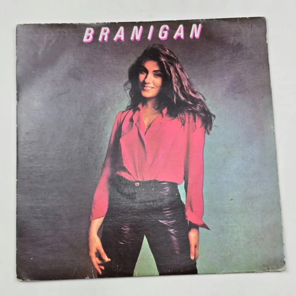 Portada del álbum 'Branigan' de Laura Branigan, con la cantante sonriendo en camisa rosa y pantalones negros. by Remates Narvaja