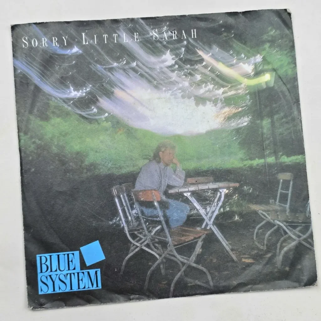 Portada del single Sorry Little Sarah de Blue System, con un hombre sentado en una mesa al aire libre. by Remates Narvaja