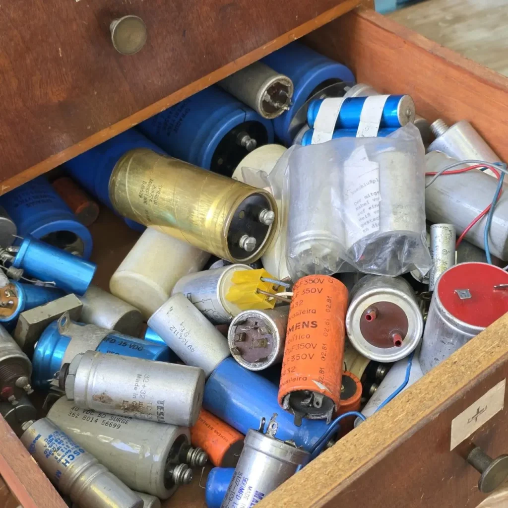 Cajón de madera lleno de capacitores electrónicos vintage variados. by Remates Narvaja