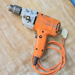 Taladro eléctrico naranja usado con su cable enrollado sobre una superficie de madera. by Remates Narvaja