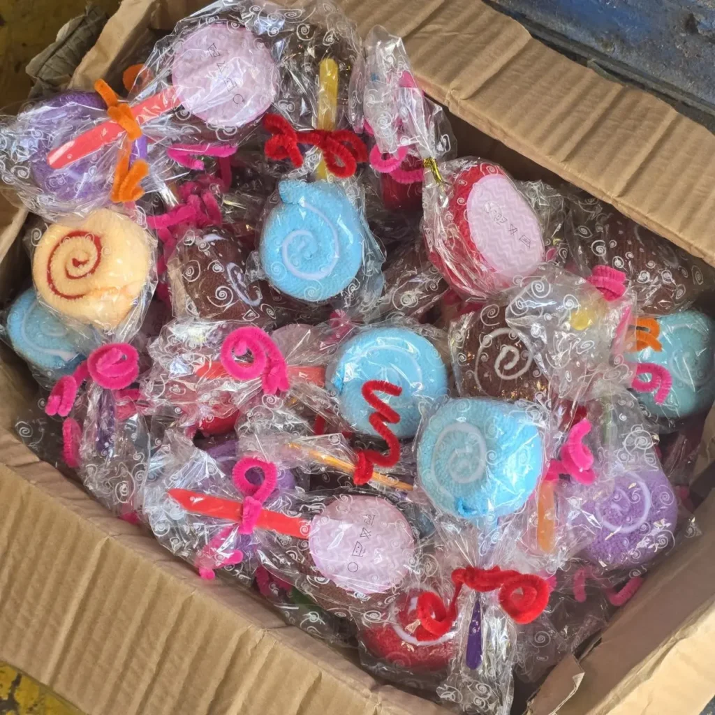 Caja con toallas de mano enrolladas de colores variados, con forma de piruletas y envueltas individualmente. by Remates Narvaja