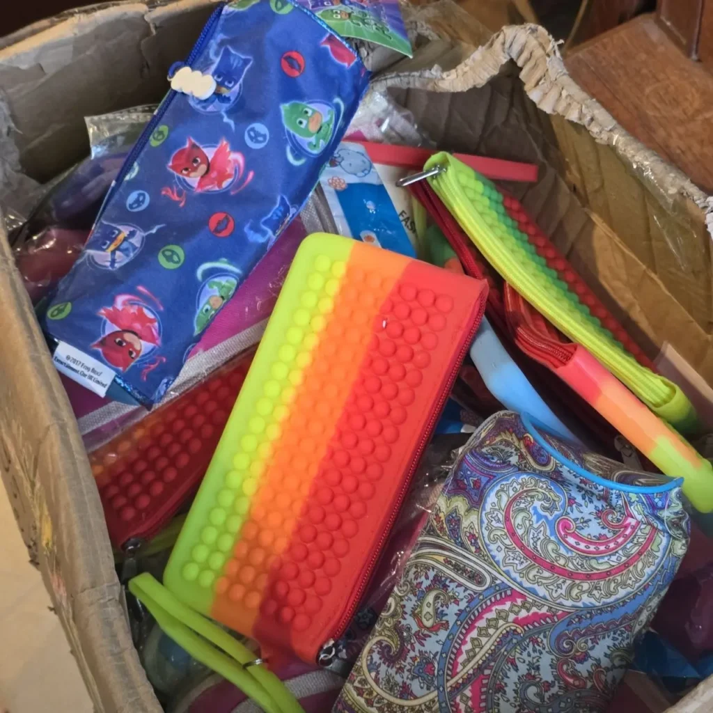 Surtido de estuches coloridos en una caja, incluyendo diseños de PJ Masks y silicona pop-it arcoíris. by Remates Narvaja