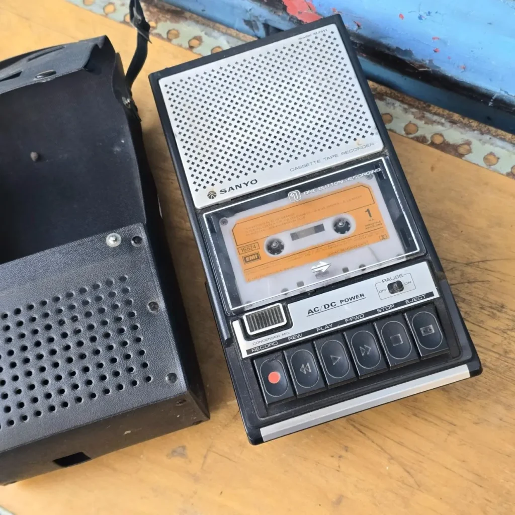 Grabadora de casetes Sanyo vintage modelo M2511 con un casete naranja insertado y su funda negra. by Remates Narvaja