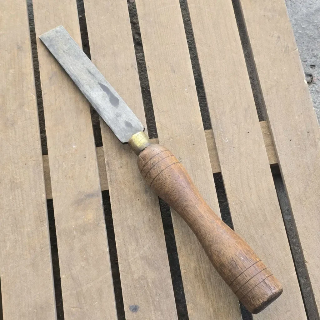 Cincel de carpintería antiguo con hoja de metal y mango de madera sobre tablas. by Remates Narvaja