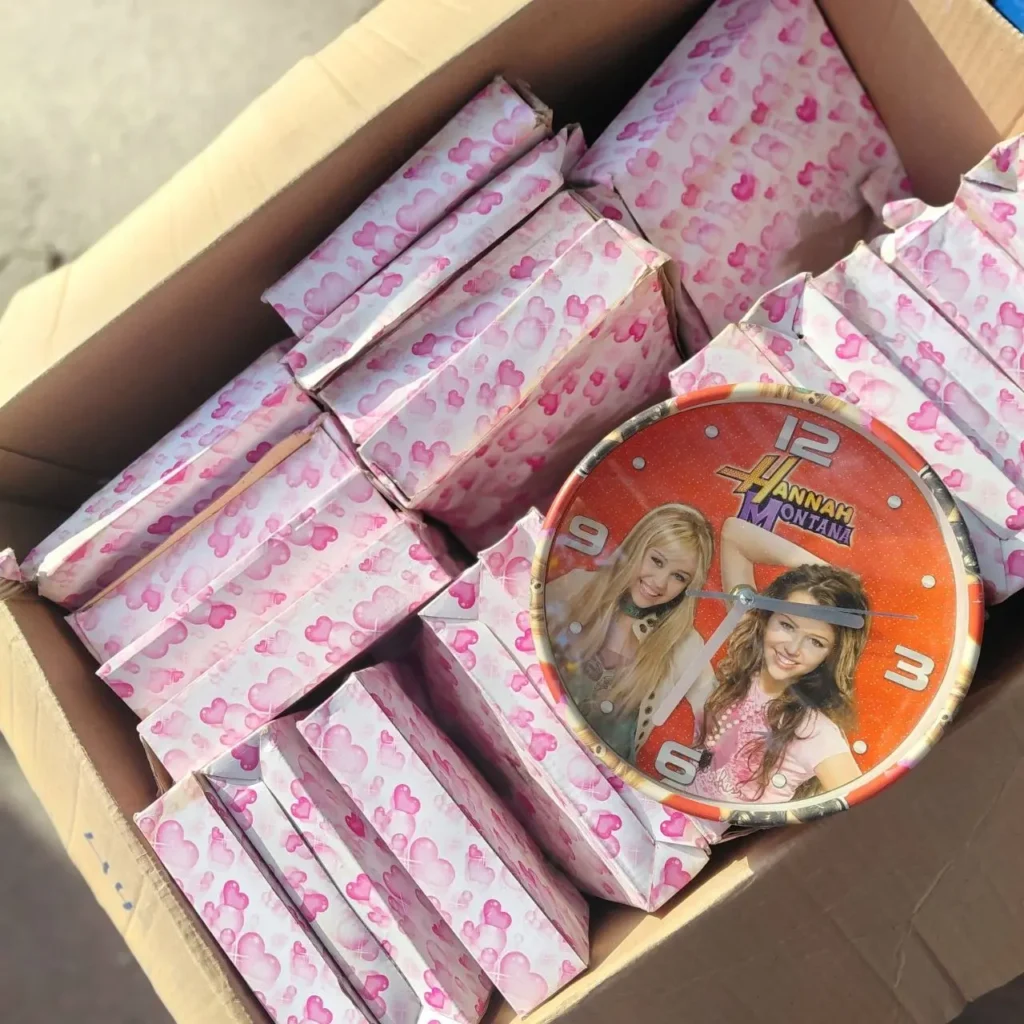 Caja de cartón llena de regalos envueltos en papel de corazones rosas y un reloj de Hannah Montana con Miley Cyrus." by Remates Narvaja