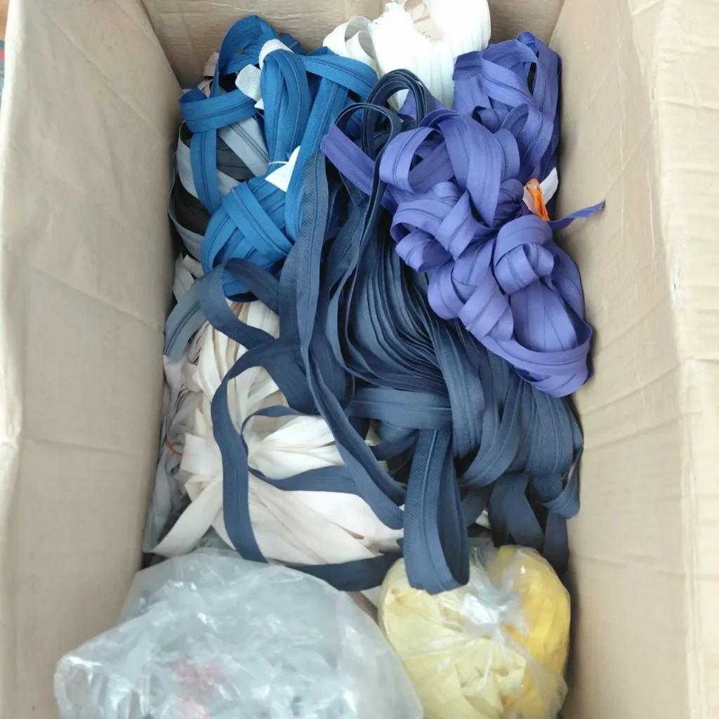 Cremalleras de varios colores (azul, morado, blanco) en una caja de cartón. by Remates Narvaja