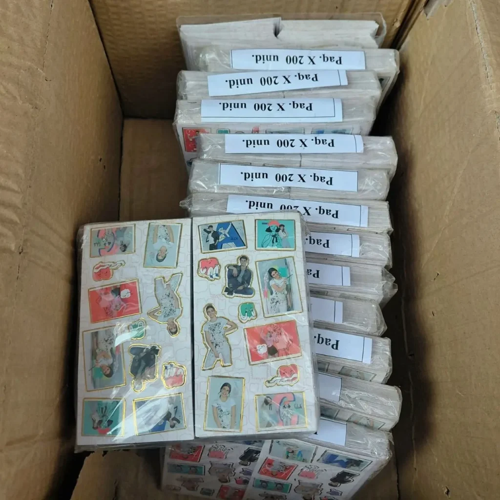 Caja de cartón llena de paquetes de 200 stickers decorativos con imágenes de personas y diseños variados. by Remates Narvaja