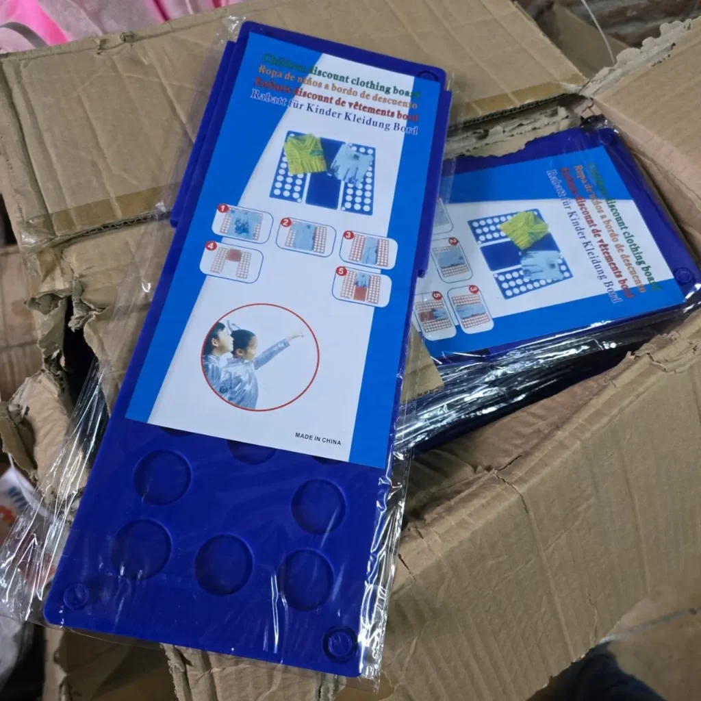 Tablas azules de plástico para doblar ropa infantil en una caja. by Remates Narvaja