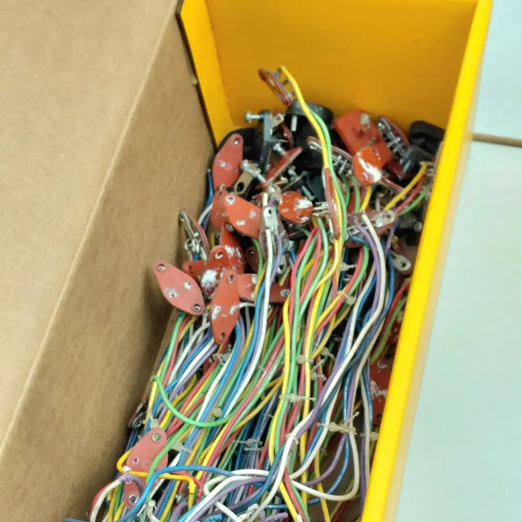 Caja amarilla llena de cables eléctricos multicolores y componentes electrónicos rojos. by Remates Narvaja