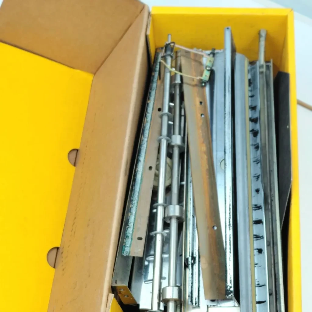 Caja amarilla con un surtido de piezas y componentes metálicos. by Remates Narvaja