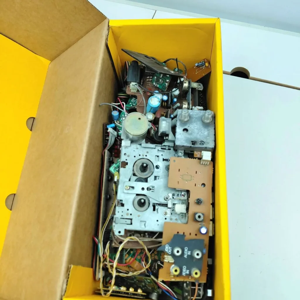 Componentes electrónicos internos de un VCR o reproductor de cinta en una caja amarilla. by Remates Narvaja