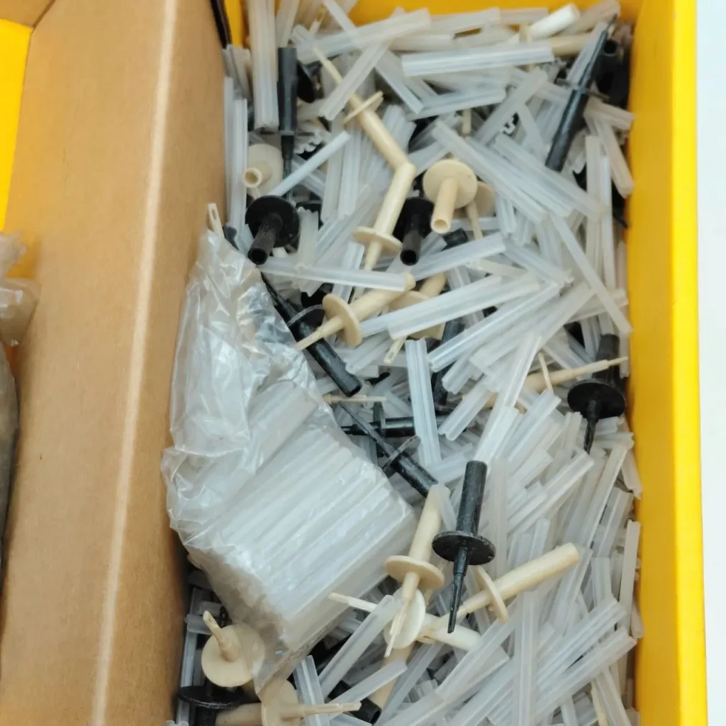 Assortment of clear plastic tubes and black and beige plastic connectors in a box. by Remates Narvaja