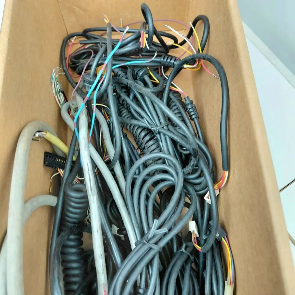 Caja de cartón con una pila de cables electrónicos enredados y de varios colores. by Remates Narvaja