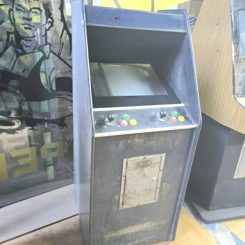 Máquina arcade retro negra y desgastada con dos joysticks y botones. by Remates Narvaja