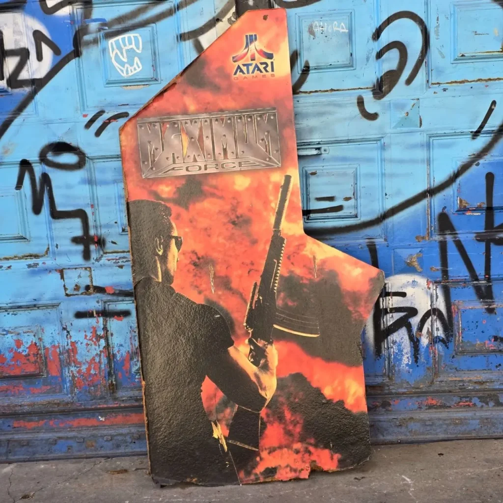 Arte de gabinete arcade vintage de Maximum Force de Atari Games con un hombre y un rifle, apoyado en una puerta azul con grafitis. by Remates Narvaja