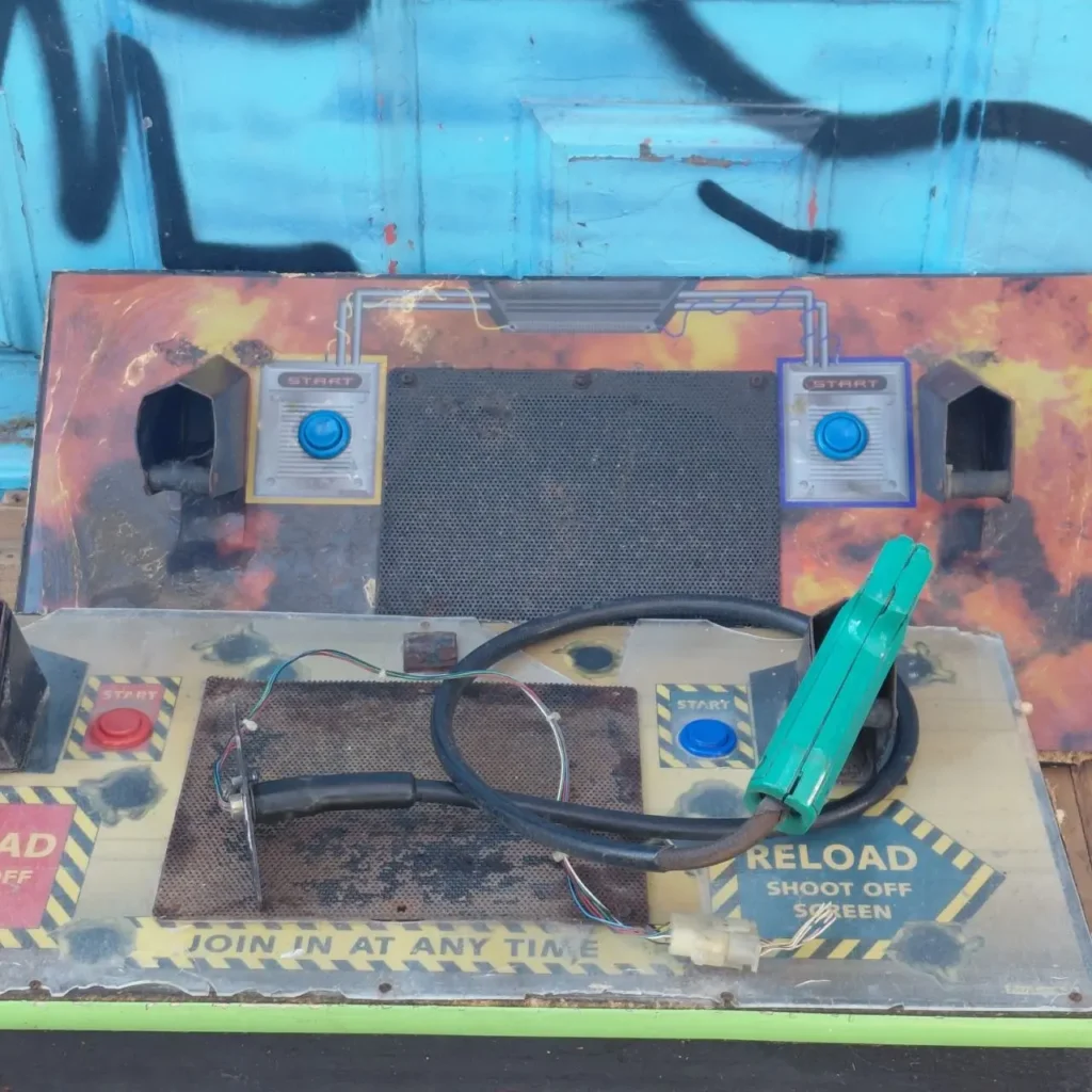 Panel de control desgastado de máquina recreativa de disparos con botones de inicio, instrucciones de recarga y pistola de luz. by Remates Narvaja