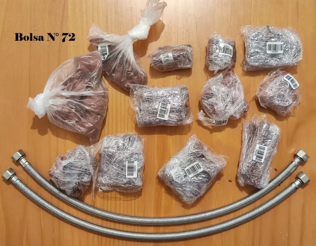 Paquetes de material rojizo envueltos en plástico con códigos de barras, dos mangueras flexibles de metal y el texto "Bolsa N by Remates Narvaja