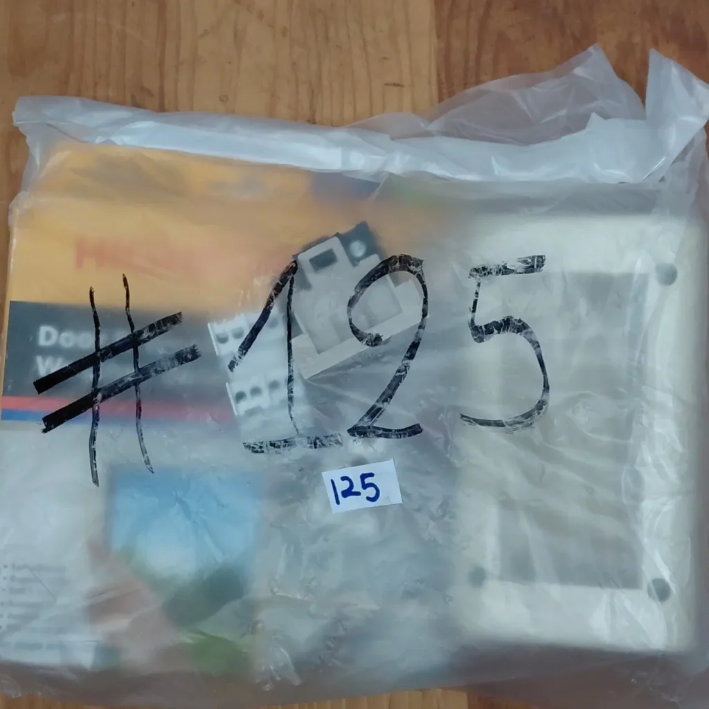 Bolsa de plástico transparente con componentes electrónicos para puerta, un paquete amarillo y la inscripción #125. by Remates Narvaja