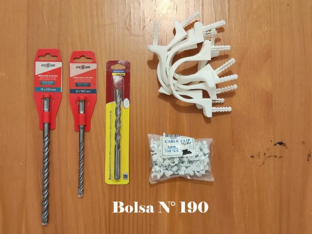 Brocas SDS para concreto y mampostería, junto con clips y abrazaderas para cable de varios tamaños, sobre una superficie de madera. by Remates Narvaja