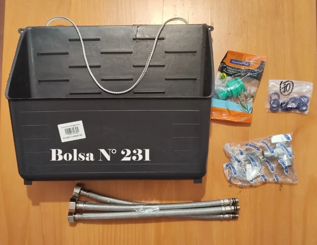 Suministros de plomería: mangueras, conectores, válvulas y sellos junto a una caja plástica negra. by Remates Narvaja