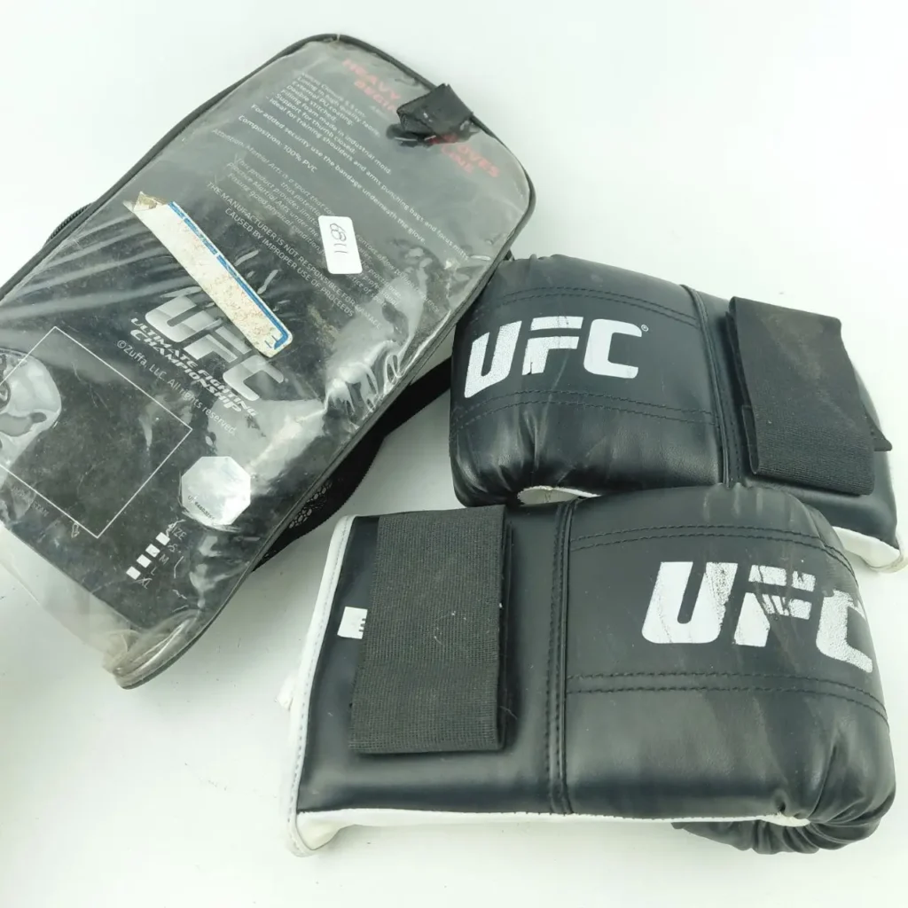 Par de guantes negros UFC para saco pesado de principiante con logo blanco y su empaque transparente. by Remates Narvaja