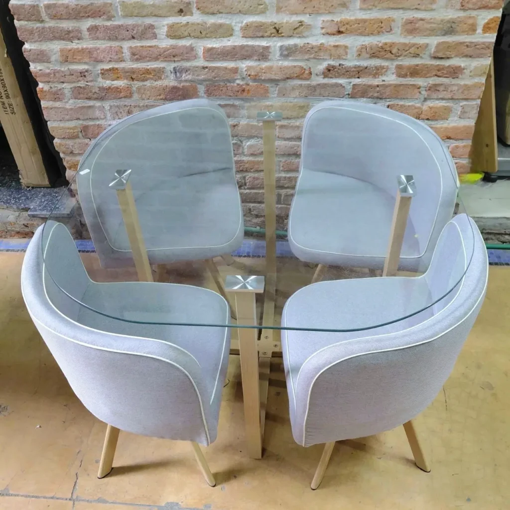 Juego de comedor moderno con mesa de cristal y cuatro sillas tapizadas en gris claro. by Remates Narvaja