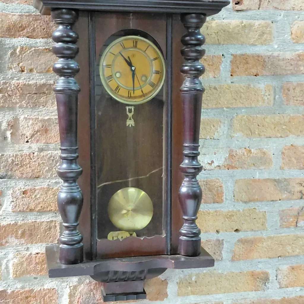 Reloj de pared antiguo de madera oscura con péndulo y esfera dorada. by Remates Narvaja