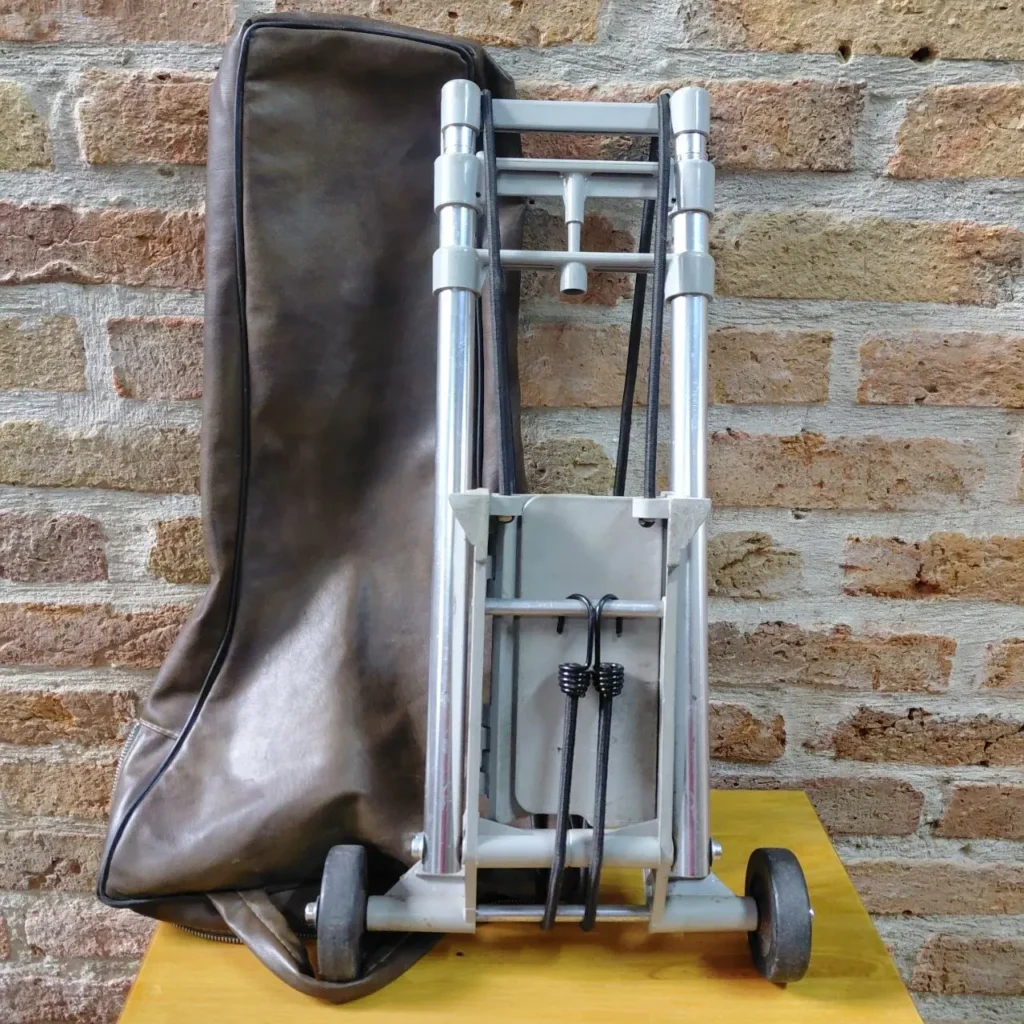 Carretilla de mano plegable gris con ruedas y su funda de transporte marrón. by Remates Narvaja