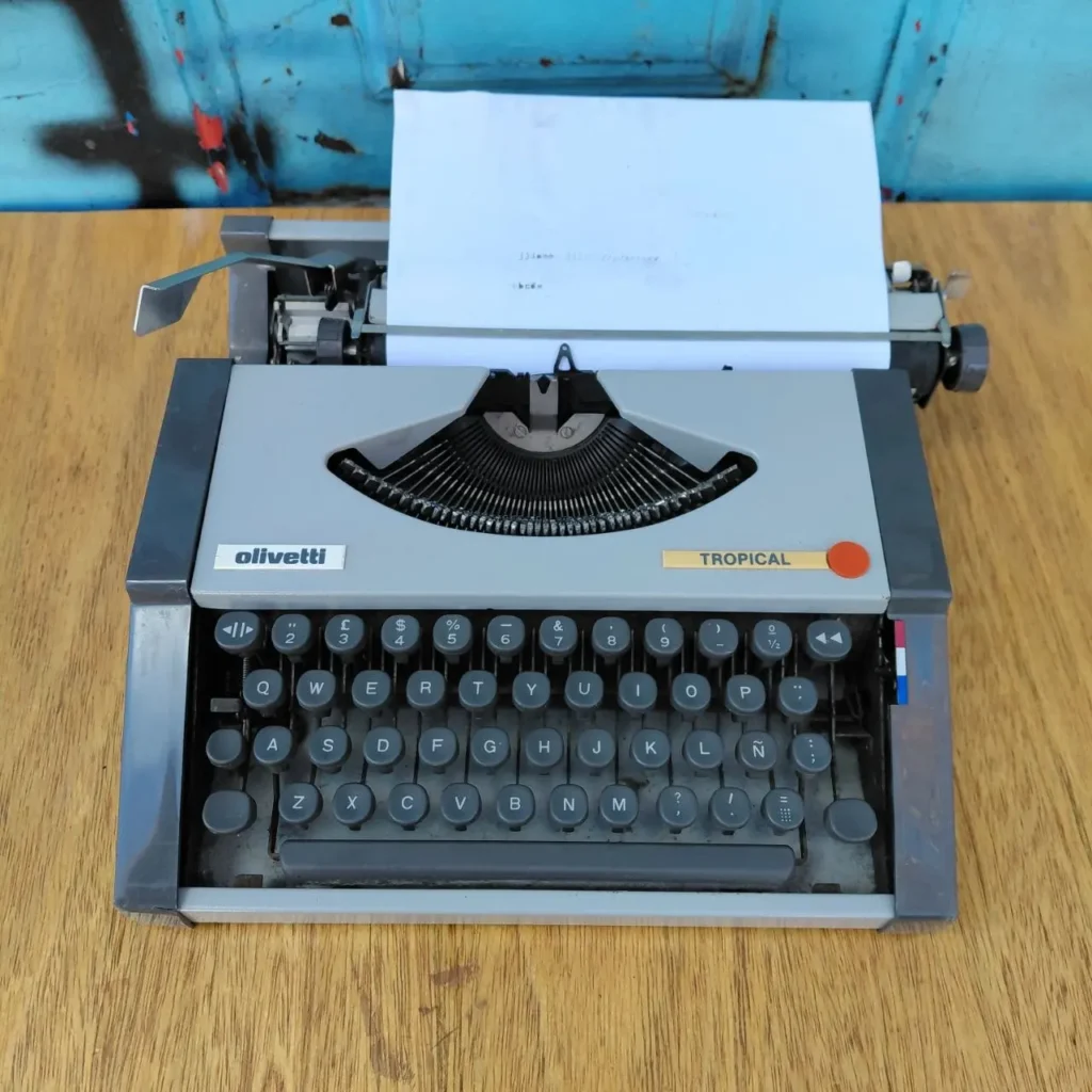Máquina de escribir vintage Olivetti Tropical gris con papel. by Remates Narvaja
