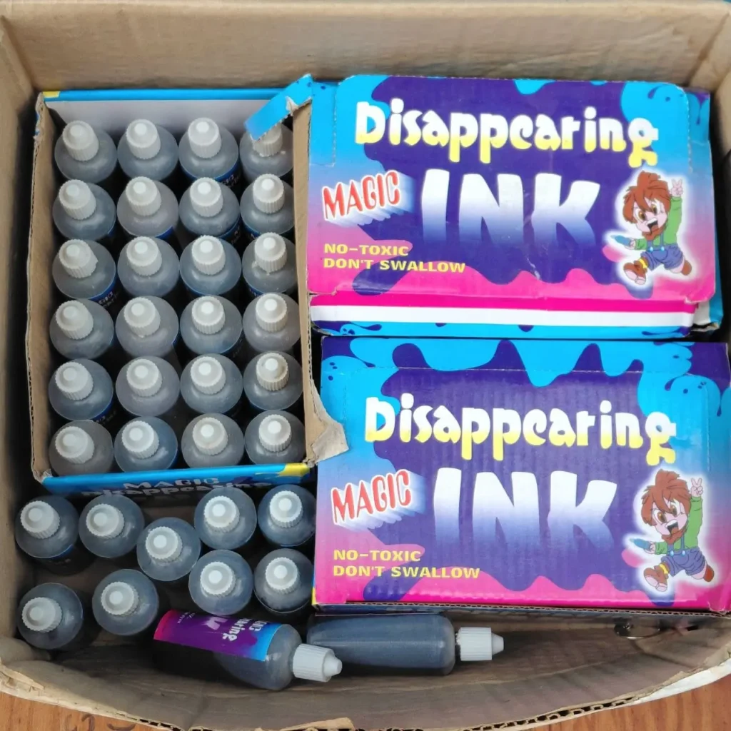 Caja de cartón con múltiples botellas pequeñas de tinta mágica que desaparece y dos cajas de producto "Disappearing MAGIC INK". by Remates Narvaja