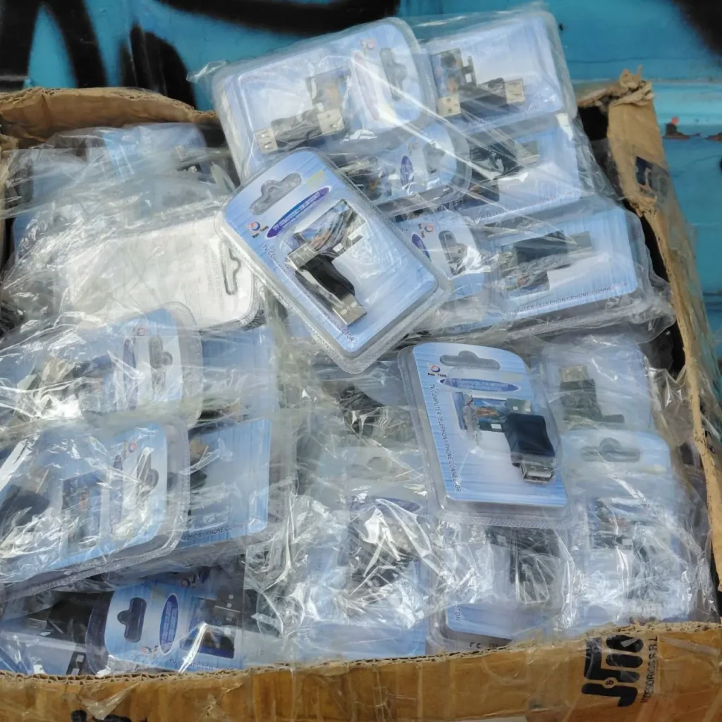 Caja de cartón llena de adaptadores y conectores USB para TV, computadora y telefonía, empaquetados individualmente. by Remates Narvaja