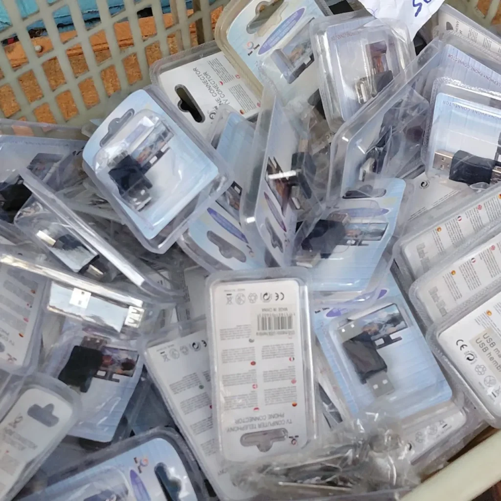 Cesta con adaptadores USB y conectores electrónicos en sus empaques. by Remates Narvaja