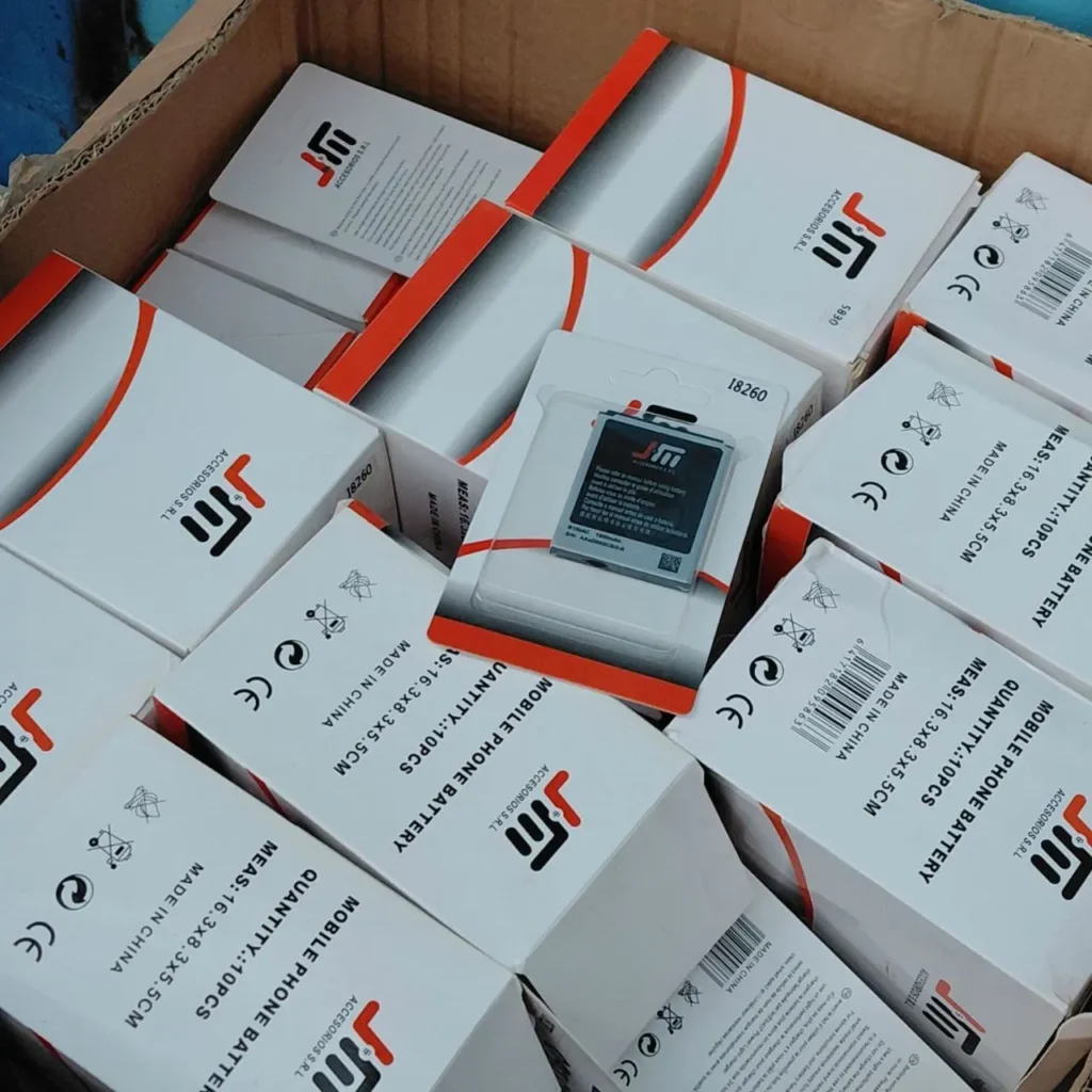 Cajas de baterías para teléfonos móviles JTM apiladas en un contenedor. by Remates Narvaja