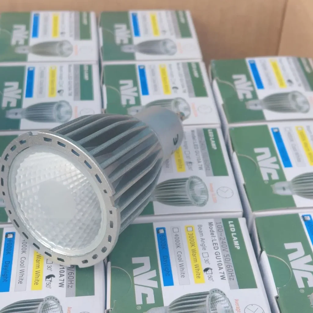 NVC LED lamp GU10A 7W with boxes stacked in the background, showing 3000K, 4000K, and 6000K options. by Remates Narvaja