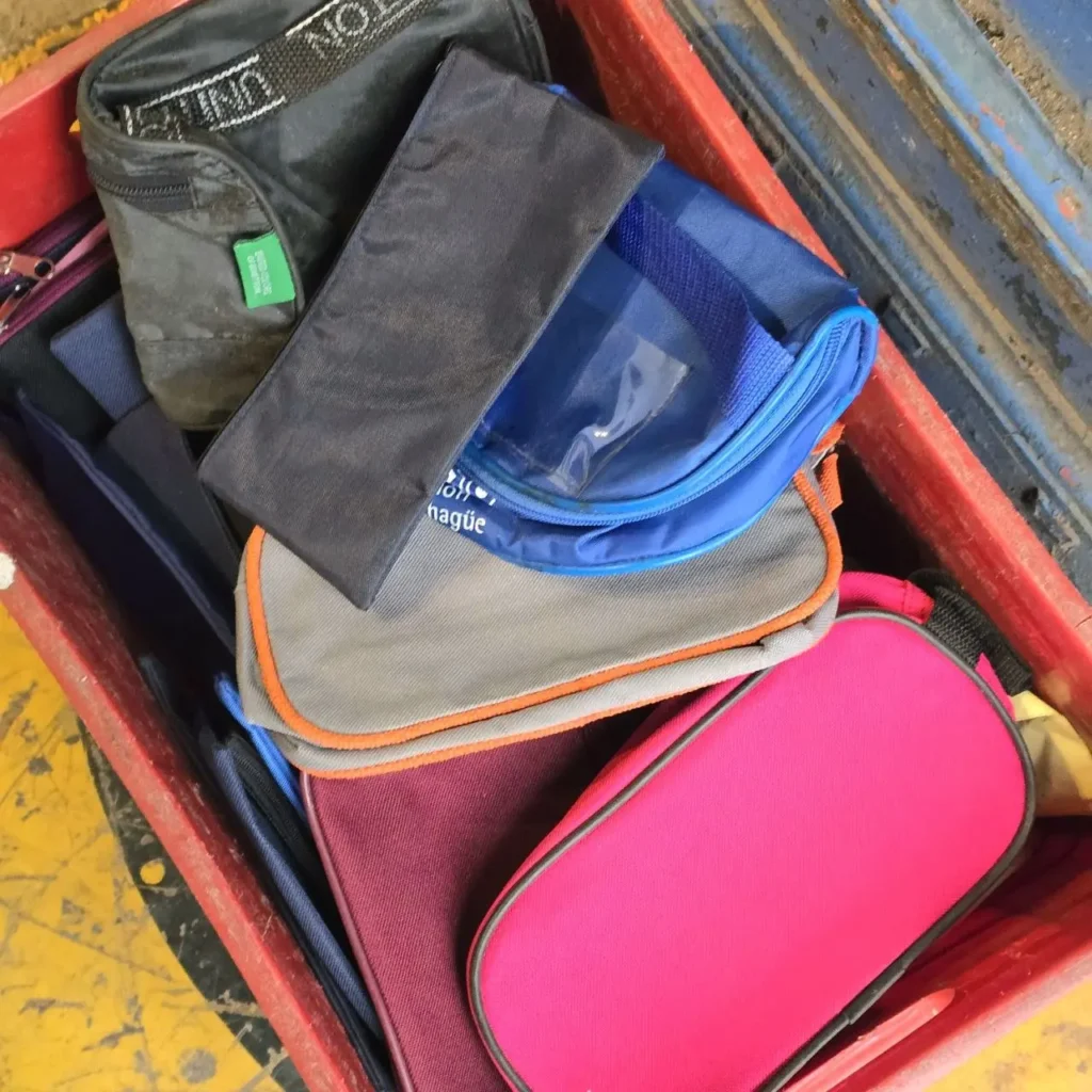 Varias bolsas y estuches de colores (negro, azul, rosa) apilados en un cajón rojo. by Remates Narvaja