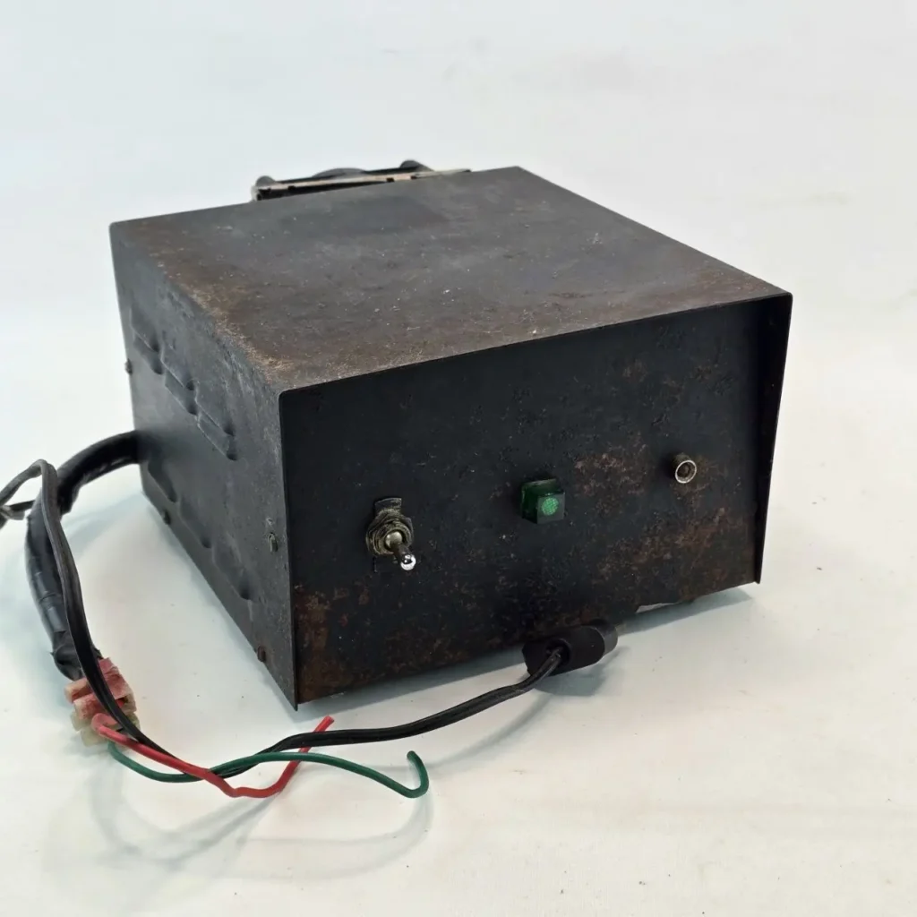 Caja metálica negra desgastada con interruptor, luz verde y cables. by Remates Narvaja