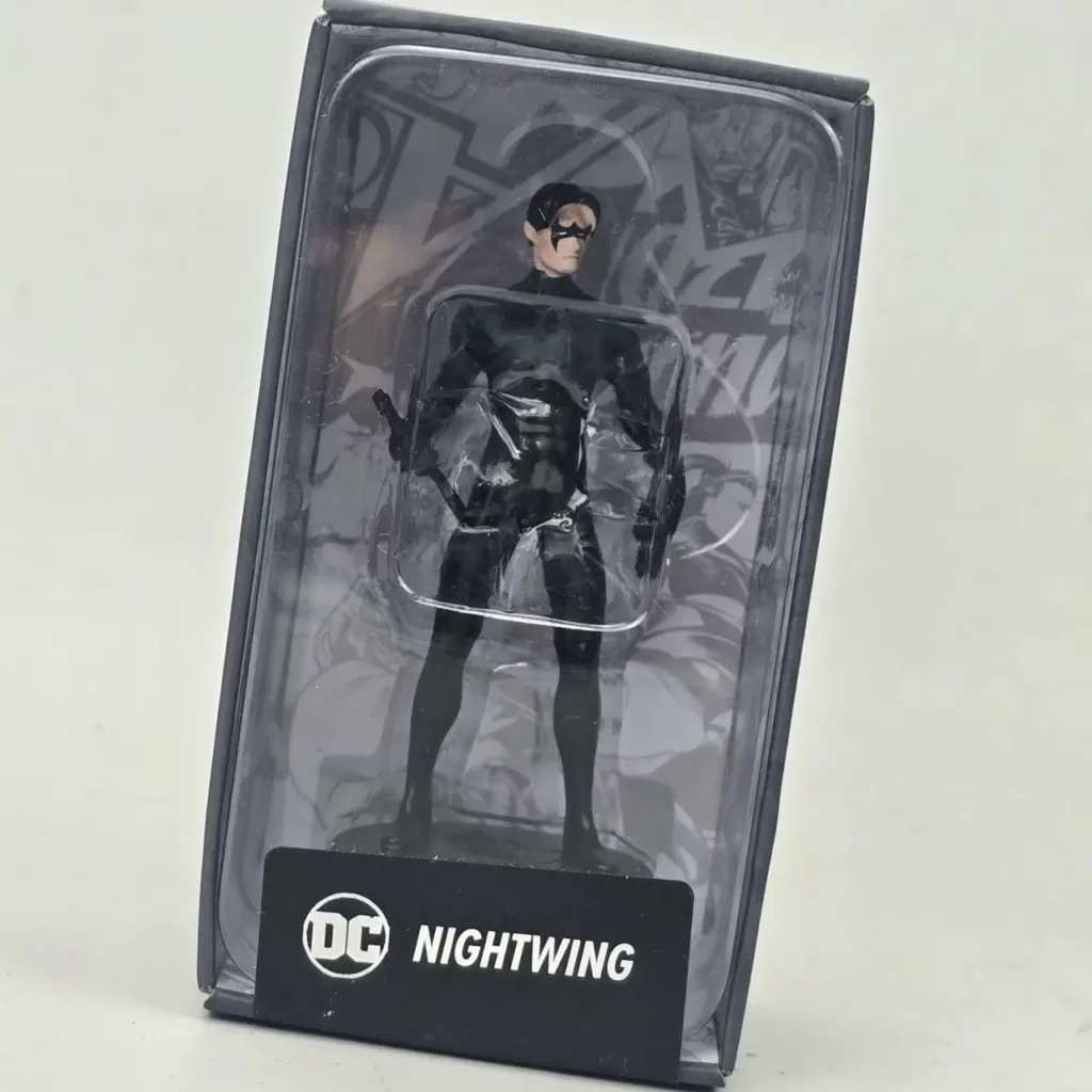 Figura de acción de Nightwing de DC Comics en su empaque original, vestido con traje negro y máscara, dentro de una caja negra con ventana transparente, by Remates Narvaja