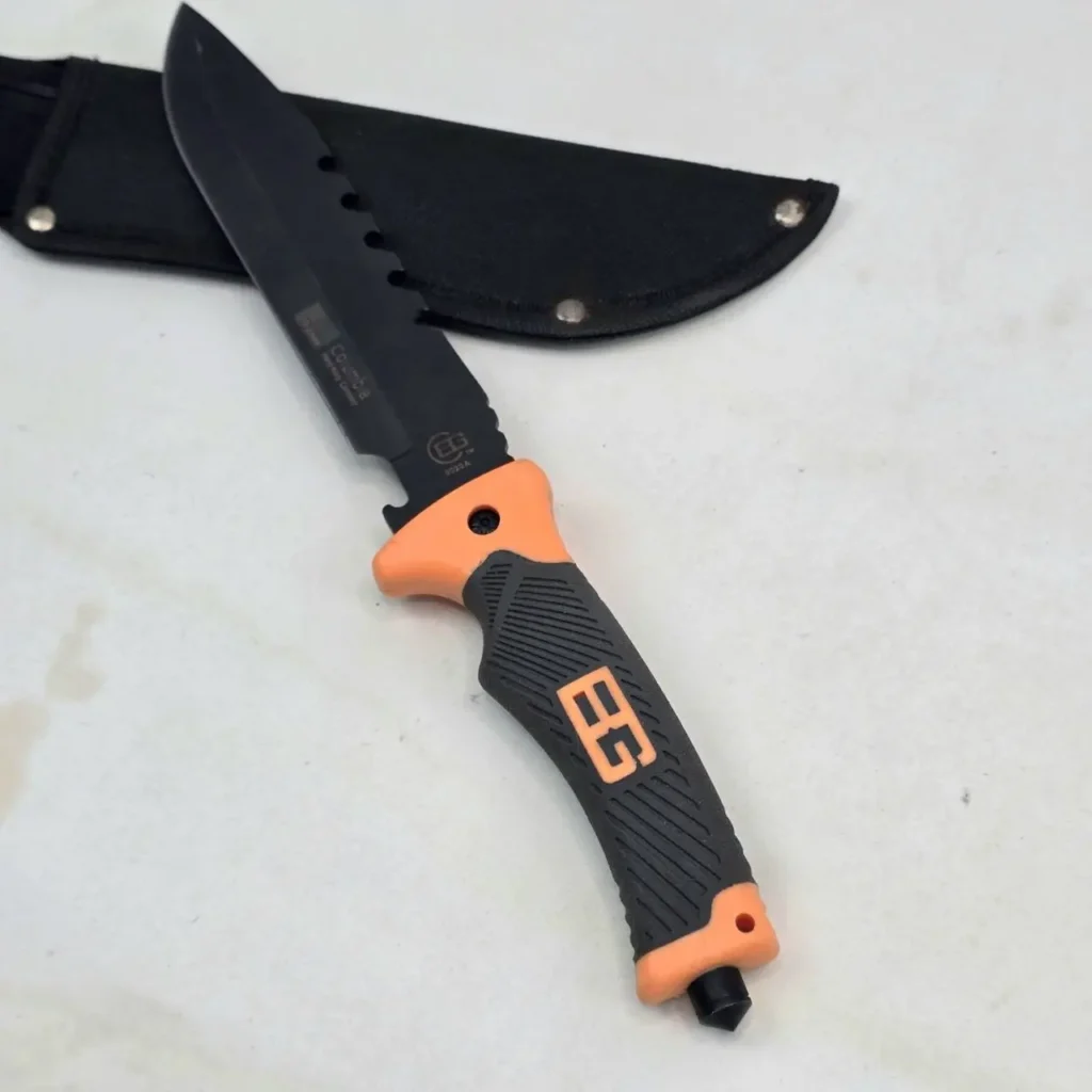 Cuchillo de supervivencia Columbia BG con hoja negra, mango naranja y negro, y funda. by Remates Narvaja