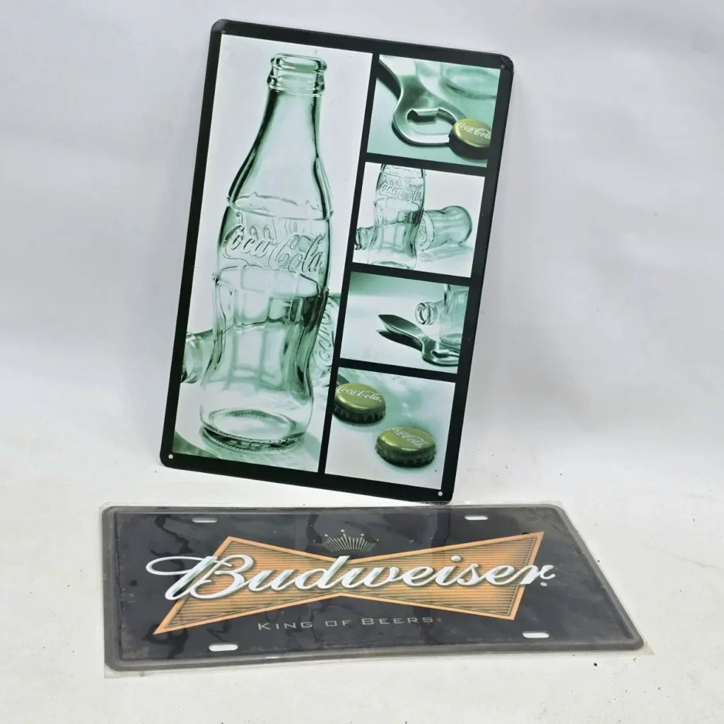 Letrero metálico de Coca-Cola con collage de botellas y una placa decorativa de Budweiser "King of Beers". by Remates Narvaja