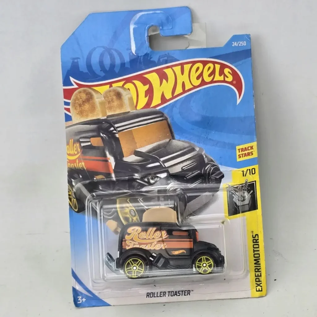 Hot Wheels Roller Toaster, coche de juguete die-cast negro con detalles naranjas y ruedas amarillas, en su empaque original sellado de la serie by Remates Narvaja