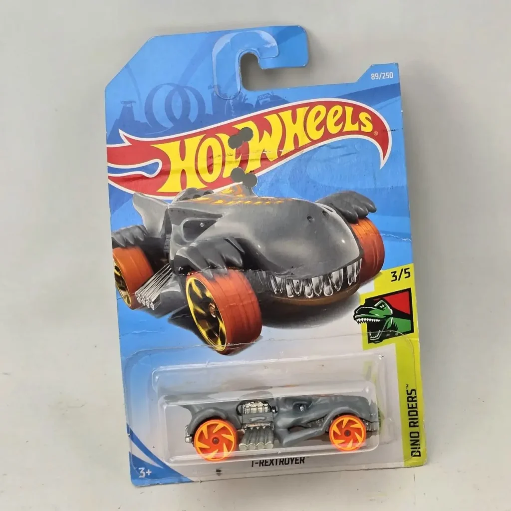 Hot Wheels T-REXtruyer diecast car, un vehículo gris con temática de dinosaurio y ruedas naranjas, en su empaque original azul by Remates Narvaja