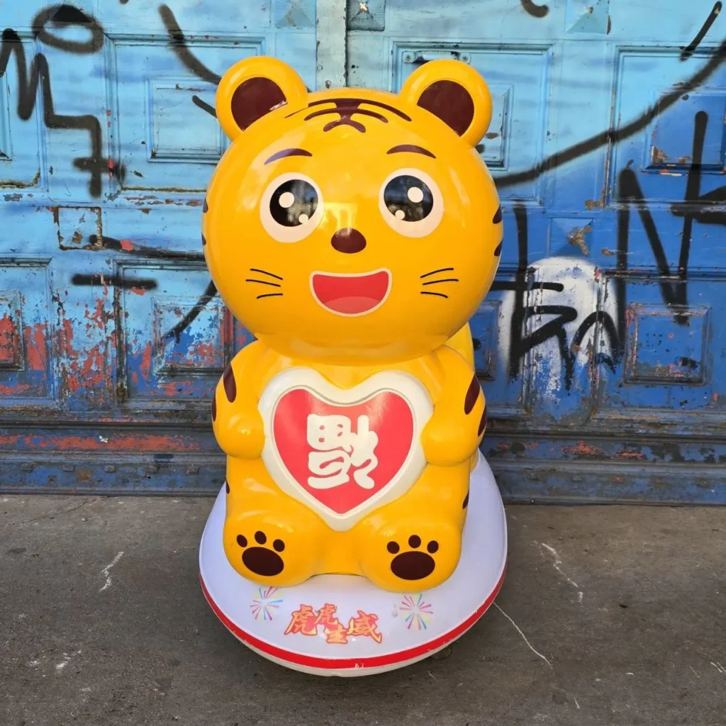 Estatua de tigre amarillo de dibujos animados con un corazón rojo y carácter chino en el pecho, sobre una base blanca, frente a una puerta by Remates Narvaja