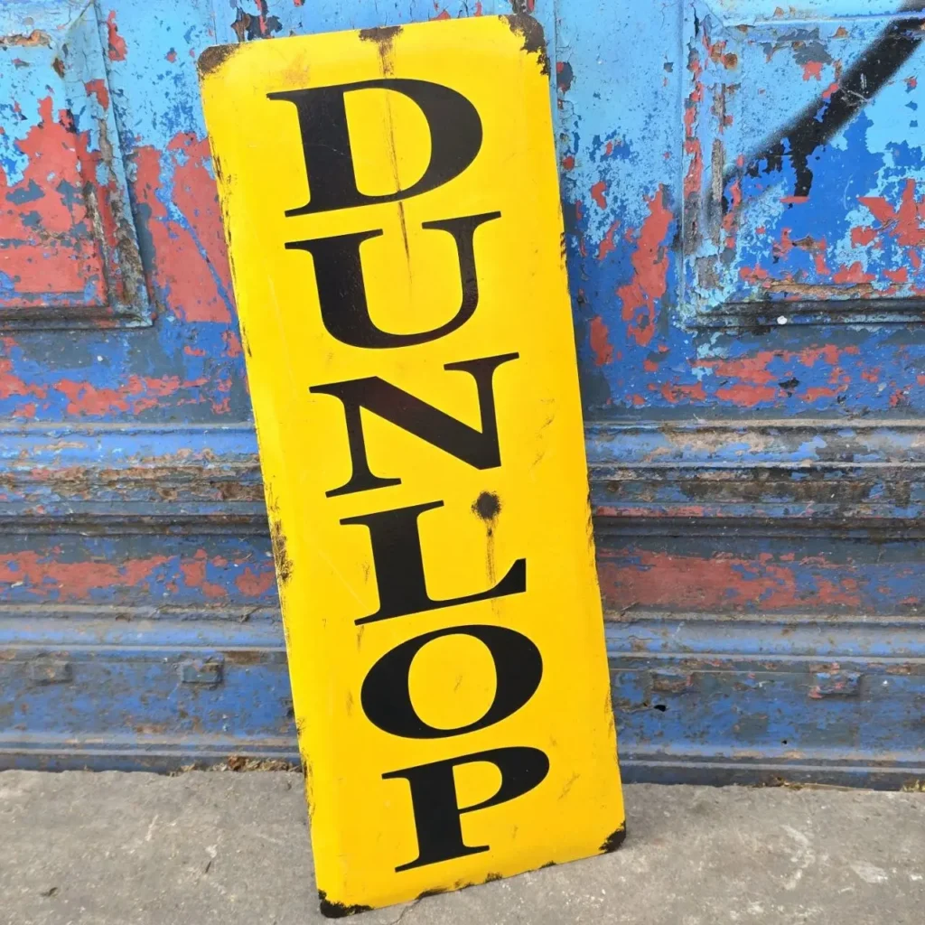 Cartel vintage amarillo Dunlop con letras negras, desgastado. by Remates Narvaja