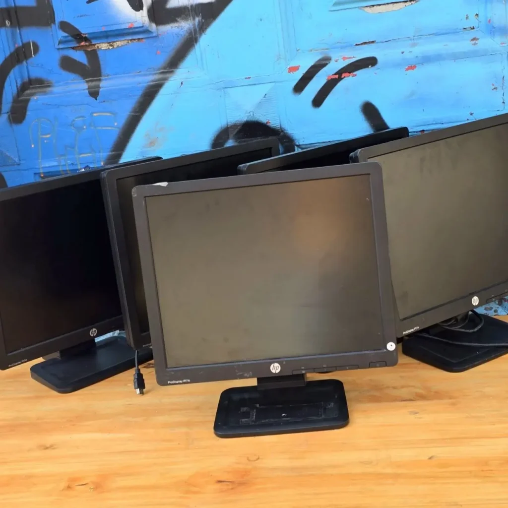 Varios monitores de computadora HP sobre una mesa de madera. by Remates Narvaja