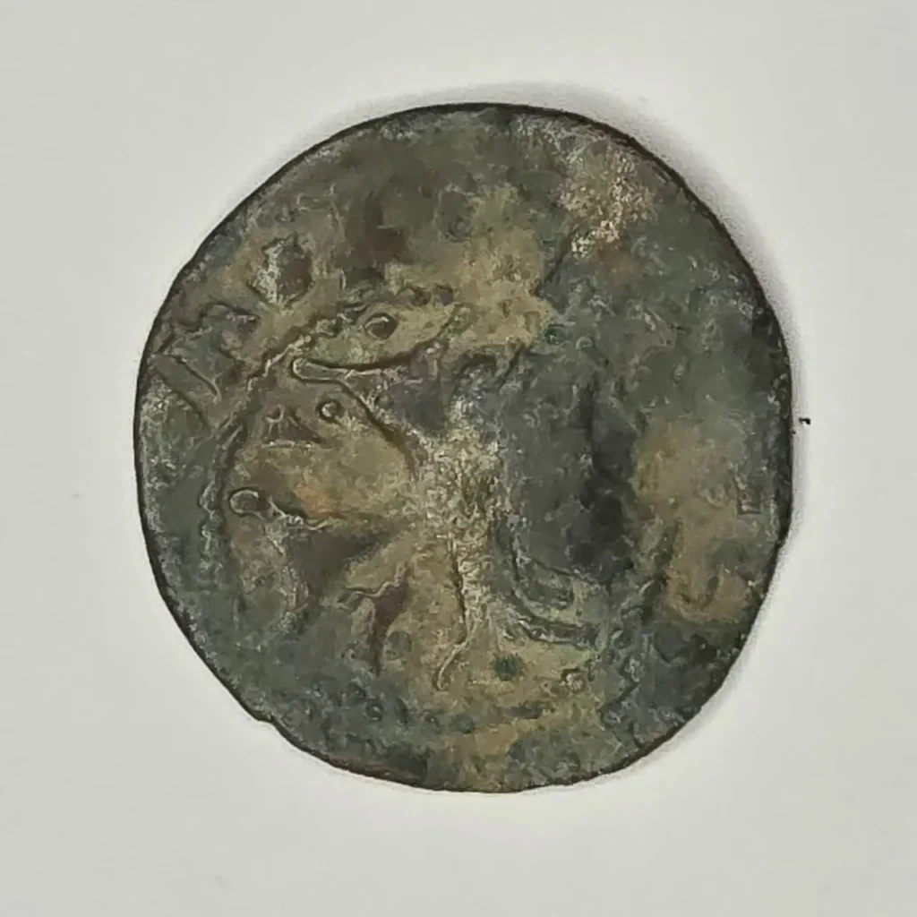 Moneda antigua de bronce con pátina, mostrando un perfil desgastado e indescifrable. by Remates Narvaja