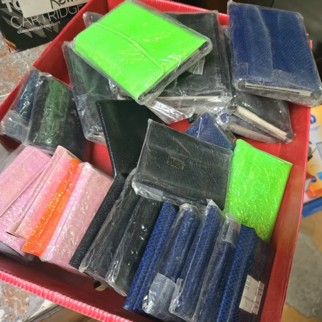 Caja con surtido de estuches o carteras pequeñas, envueltas individualmente en plástico, en colores verde, azul, rosa by Remates Narvaja