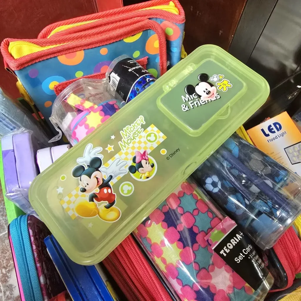 Contenedor verde de Mickey Mouse y Minnie Mouse entre útiles escolares y bolsas coloridas. by Remates Narvaja