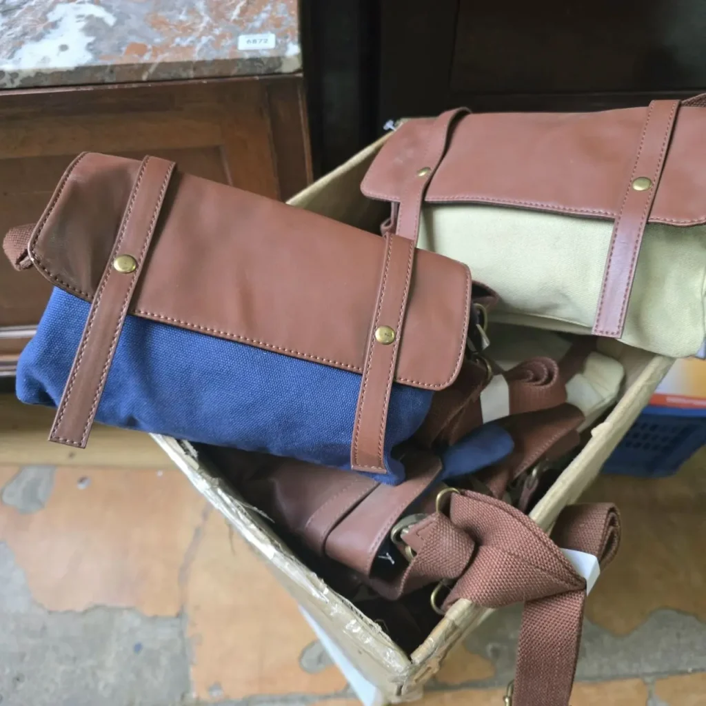 Bolsos bandolera de lona y piel con solapa, uno azul y otro beige, en una caja. by Remates Narvaja