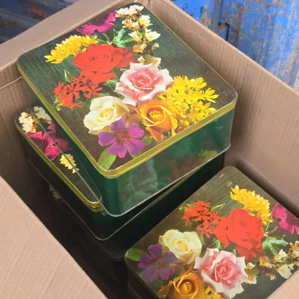 Latas decoradas verdes con diseño de ramo floral colorido en una caja de cartón. by Remates Narvaja