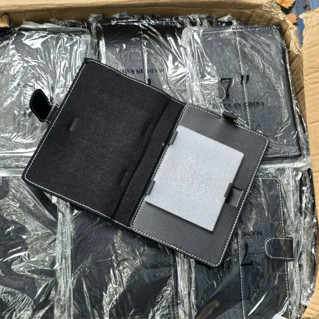Funda negra para tablet de 7 pulgadas abierta, con costuras blancas, en una caja con más fundas. by Remates Narvaja